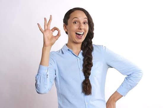 A girl with a smile on her face, showing OK with her fingers.